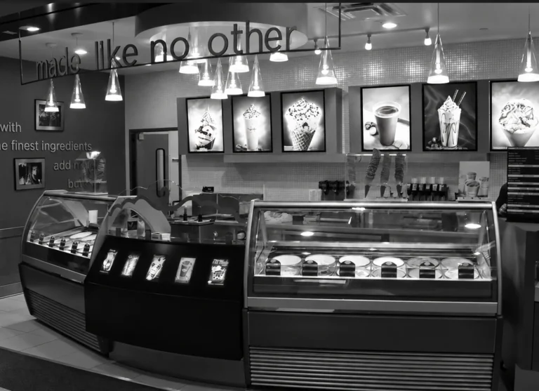 Black-and-white photo of an ice cream shop counter with curved-glass dipping cabinets, taken in 2007